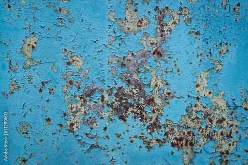 Metal fence with old blue paint. Peeled paint. Yellow, red hue with rust.