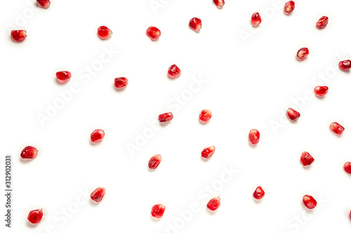 Separated pomegranate seeds scattered in a chaotic manner, isolated on white background. Food background. 