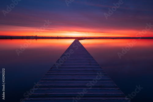 Photo Very colorful and tranquil dawn at a jetty in a lake