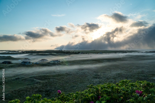 Clouds rolling in right after sunrise in the beautiful dunes of Hvide Sande in Denmark with fog in the forground