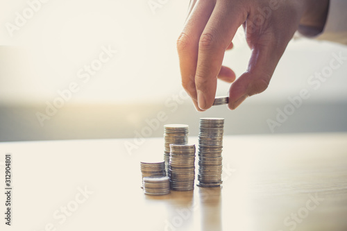 Hands put the coin on top, Businessmen prepare a financial plan by accounting income - expenses for stable business growth saving ideas, Saving money concept