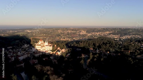 Aerial Views of the ancient city of Sintra and Palacio de Pena, Portugal. Sintra National Palace up on the hill at sunset. Drone footage track in