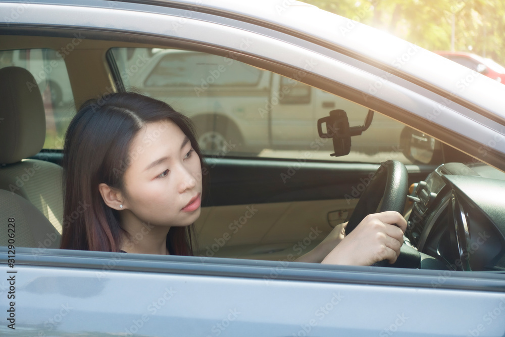 Young Asian woman is looking at front while driving traffic jammed.