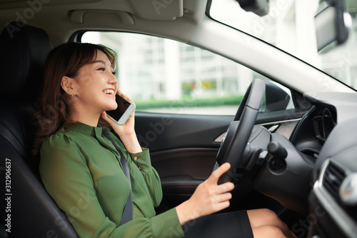 cheerful young woman driving a car and talking on the smartphone © makistock