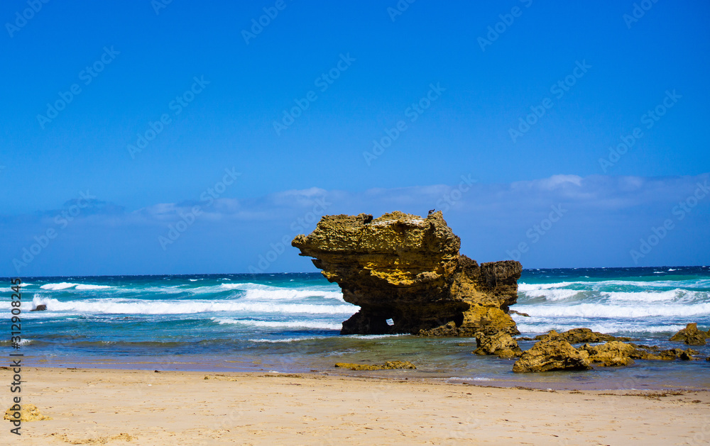 Stone at beach with blue sky in background Stone at beach with blue sky in background