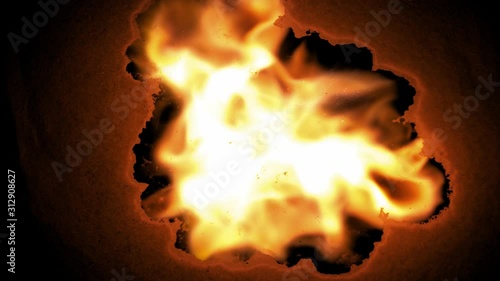 Close-up shot of burning paper of fire across the screen against a black background 