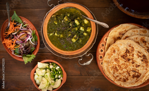 Saag Aloo- Indian potato and spinach burry served with flaky layered flat bread and side dishes