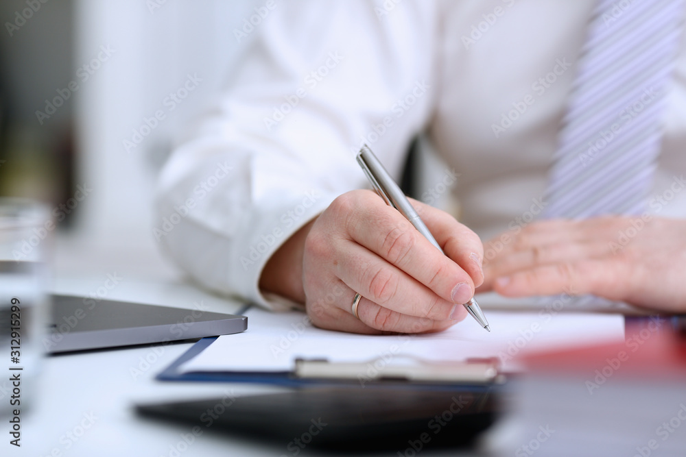 Male arm in suit and tie hold silver pen Male arm in suit and tie hold silver pen