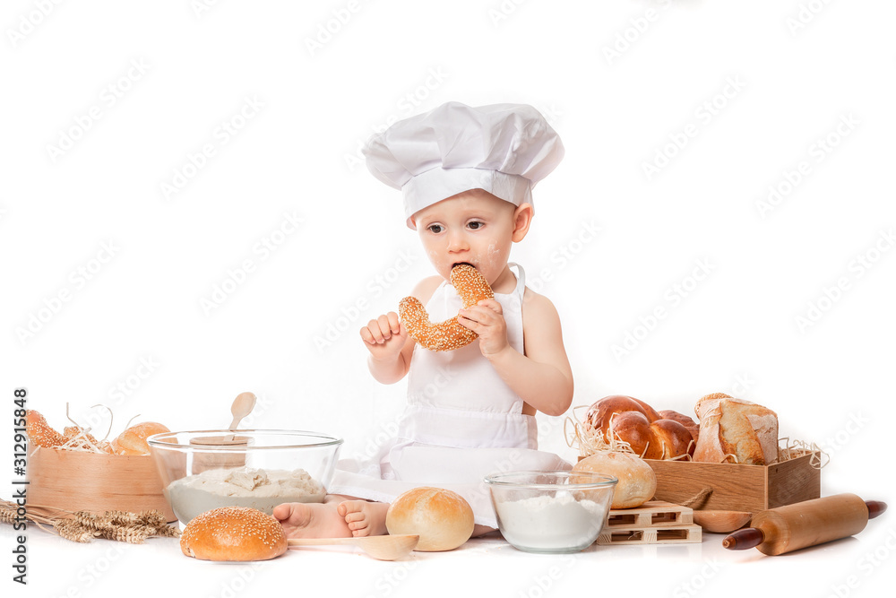 child with bread on bakery-like background wearing cook-hat. Little baker baby boy child with bread on bakery-like background wearing cook-hat. Little baker baby boy