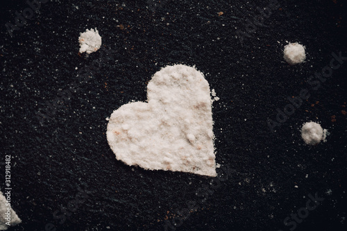 Composition with decorated heart shaped cookies on dark,black background.