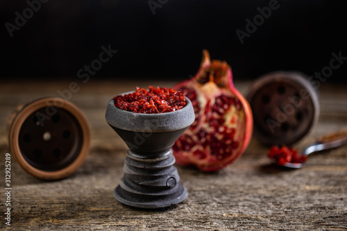 Stone hookah head on old rustic table with fruit flavoured tobacco photo