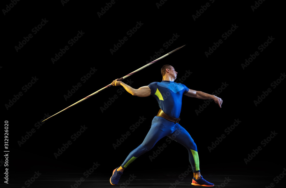 Male athlete practices in throwing javelin on black background in neon light. Professional sportsman training in action, motion. Concept of healthy lifestyle, movement, activity, competition Male athlete practices in throwing javelin on black background in neon light. Professional sportsman training in action, motion. Concept of healthy lifestyle, movement, activity, competition