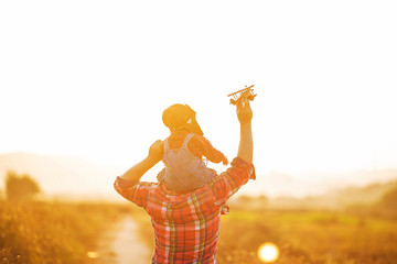 Child pilot aviator with airplane dreams of traveling in summer in nature at sunset，Happy kid playing with father. Dad and son outdoors.   Travel and vacation concept. Imagination and freedom concept