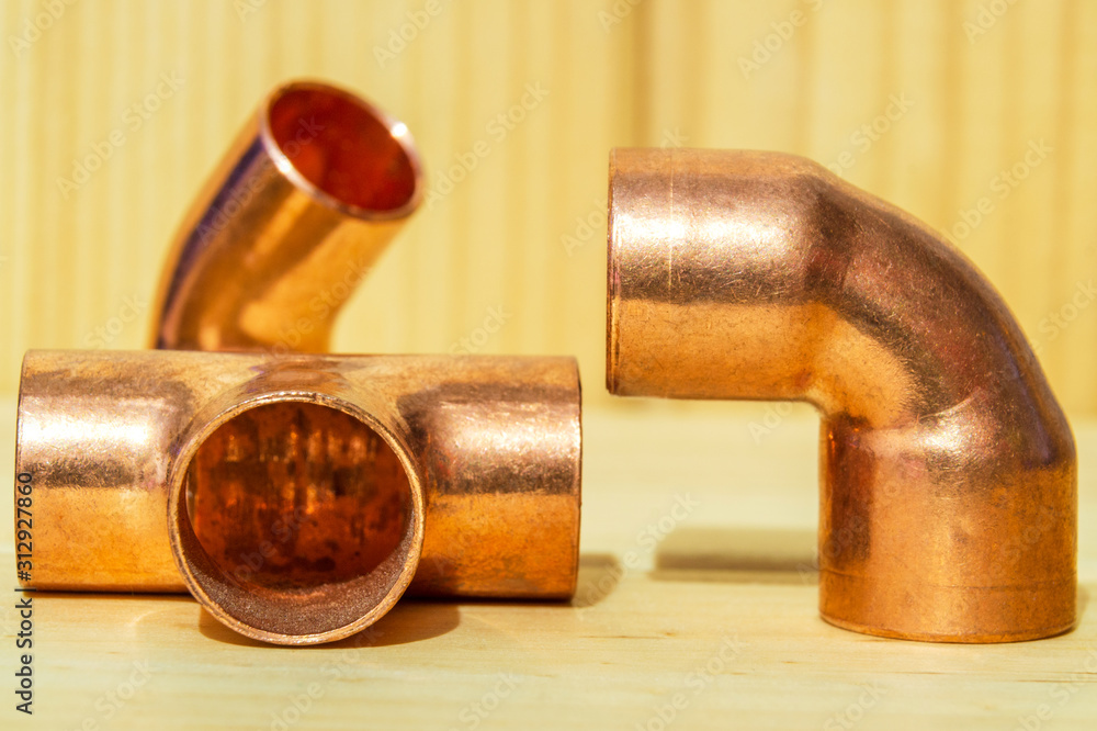 Copper water pipe fittings on wooden board plumbing concept