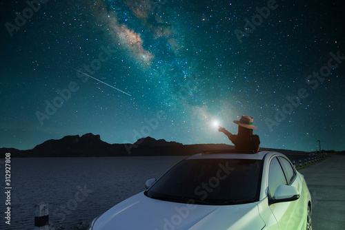 silhouette Asian women standing alone in a sunroof at the Lake Scenic spot. watching the sky and the Milky Way at night. Long exposure, with grain. photo