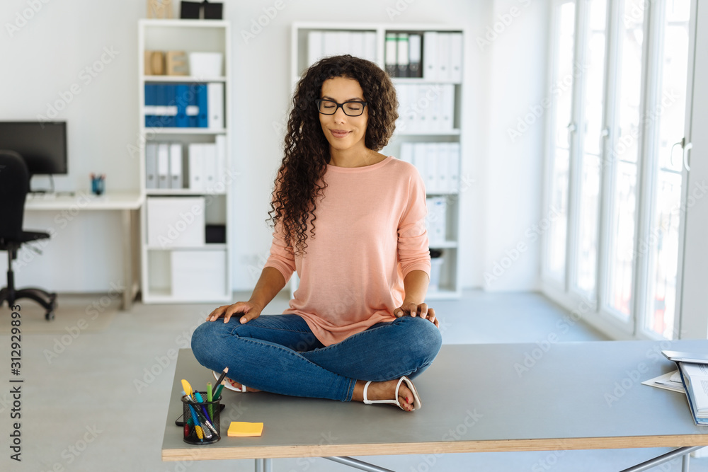 Young businesswoman sitting meditating Young businesswoman sitting meditating