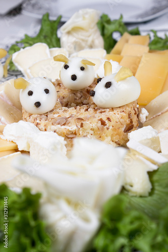 Holiday Christmas salad mouse 2020 New Year cheese piece shape on a white plate. Boiled eggs with cheese look like white mice (rats), horizontal, close up