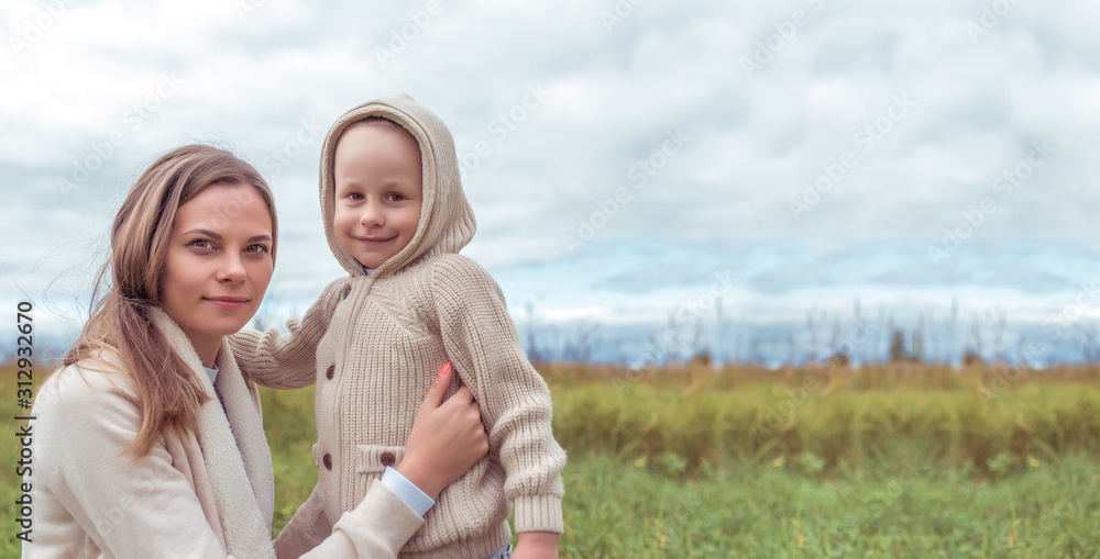 Woman mom hugs son, little boy warm casual clothes, beige sweater. Emotions tenderness caring for love, parent support, happiness, relaxation. On street autumn park field. Free space for copy text. Woman mom hugs son, little boy warm casual clothes, beige sweater. Emotions tenderness caring for love, parent support, happiness, relaxation. On street autumn park field. Free space for copy text.