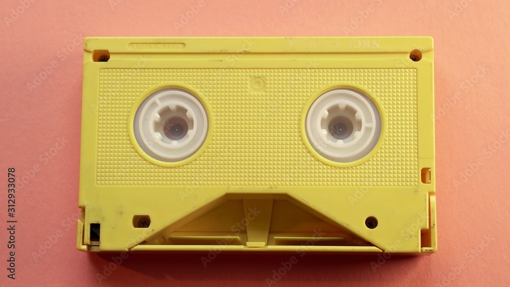 Fototapeta premium Yellow video tape on orange background, VHS, 90s concept, videotape, cassette
