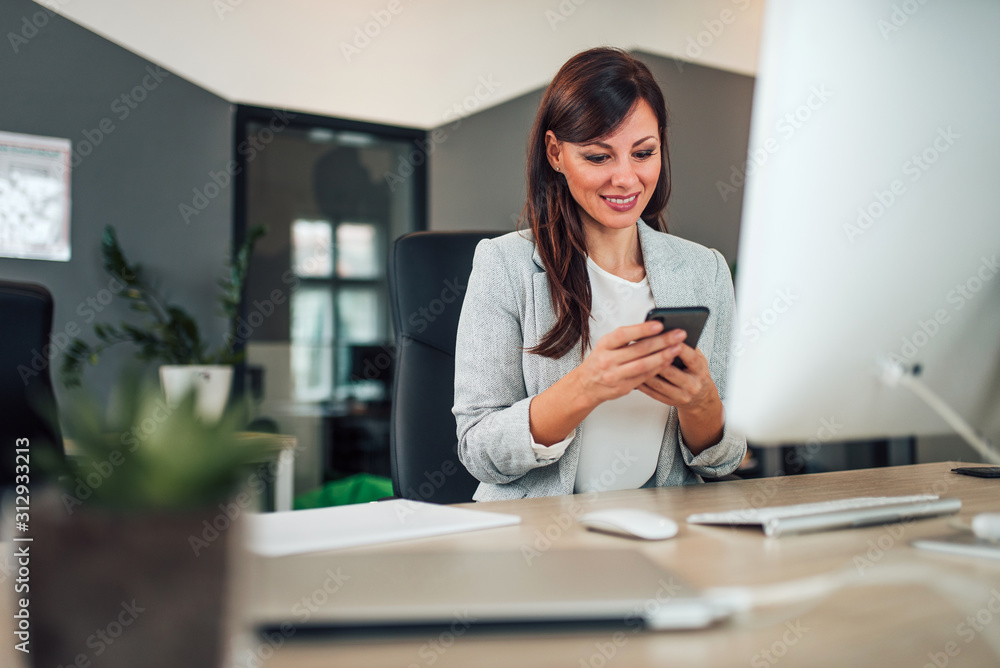 Businesswoman using smart phone in modern office, portrait. Businesswoman using smart phone in modern office, portrait.