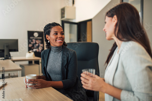 Positive female coworkers talking while working together.