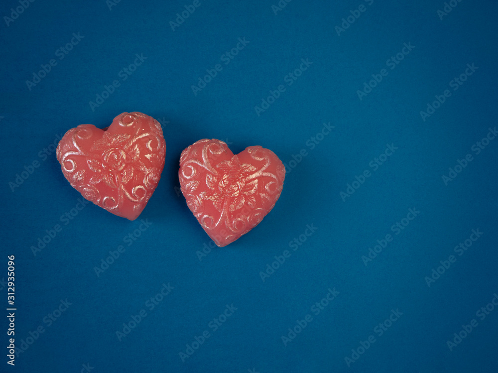 Couple of pink handmade soap in the shape of hearts on a blue background top view with copy space. Authentic romantic Valentine's day gift, symbol of love and passion.