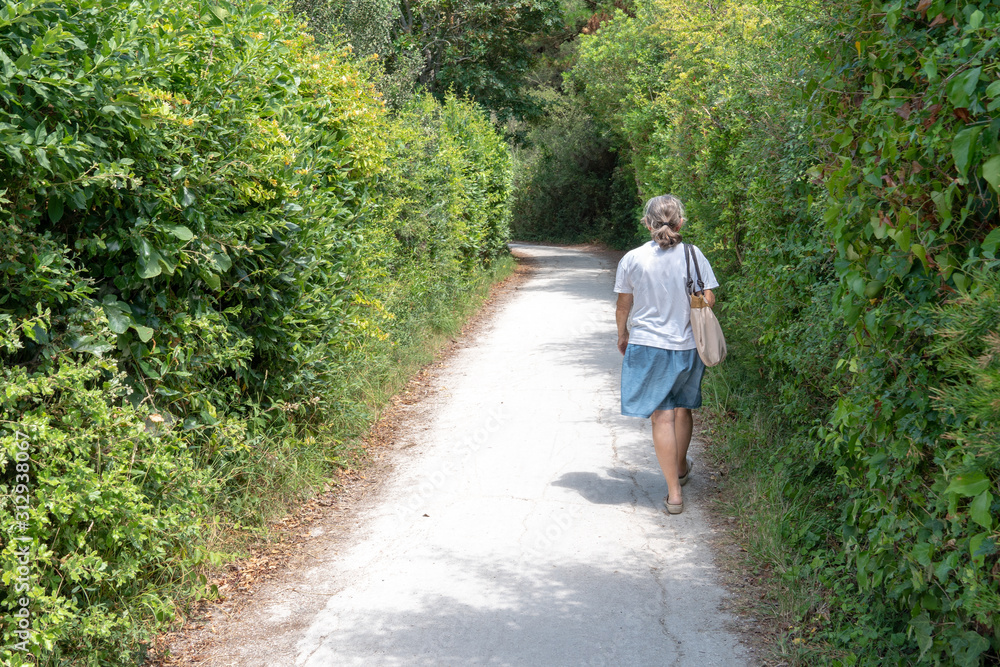 senior retired woman in pathway forest in Île d'Aix island in France senior retired woman in pathway forest in Île d'Aix island in France