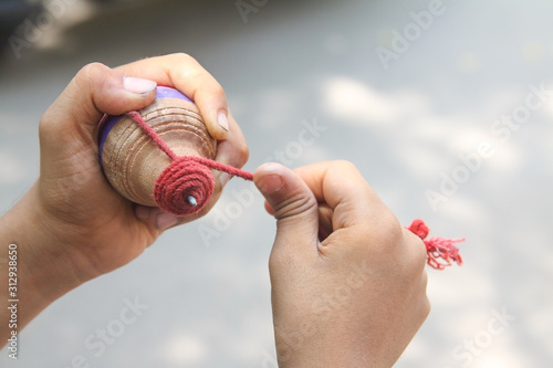 Classic wooden spinning top toy with string photo