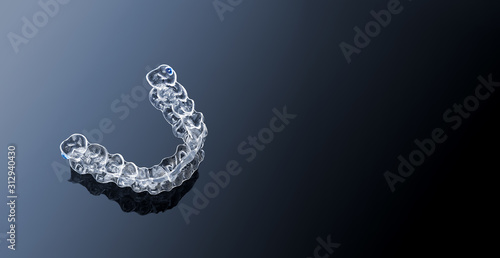 Invisible orthodontics cosmetic brackets on gradient background, tooth aligners, plastic braces. Modern teeth retainers created on a 3d printer. A way to have a beautiful smile and white teeth. photo