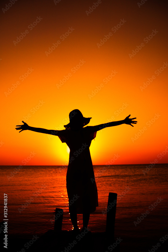 One woman silhouette Stood on the bridges of the sea towards sunset She looks happy and has power.