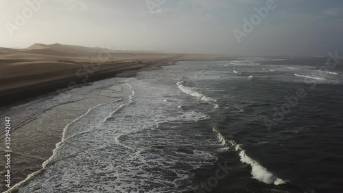 4K aerial drone video view of Namibian Atlantic coastline, Zeila L-758 Walvis Bay stranded rusty shipwreck at sand beach in Skeleton Coast Park landscape with ocean background at Namibia's west coast photo