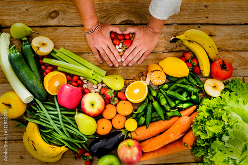 Fresh and seasonal vegatables and fruit on a woodem table with people woman hands doing love hearth with it - healthy eat lifestyle concept for vegetarian or diet weight loss activity photo