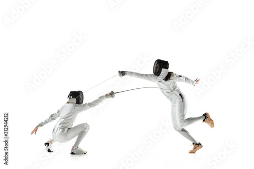 Foto Teen girls in fencing costumes with swords in hands isolated on white studio background