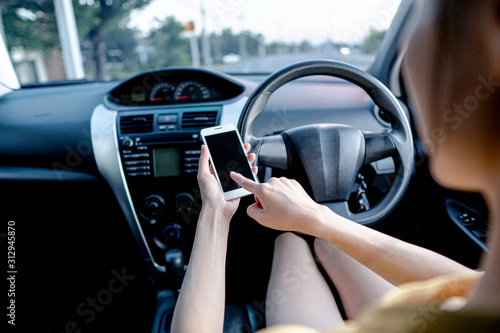 Young woman using smart phone while driving a car