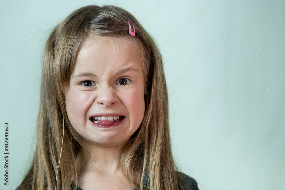 Close-up portrait of little girl with long hair making disgust expression. Close-up portrait of little girl with long hair making disgust expression.