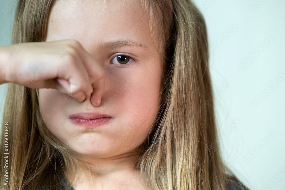 Close-up portrait of little girl with long hair holding her nose with fingers in disgust. Close-up portrait of little girl with long hair holding her nose with fingers in disgust.