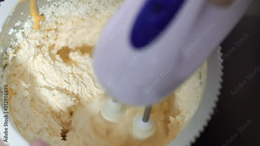 Mixer mixing whipped cream or egg cream with sugar in bowl. Concept of