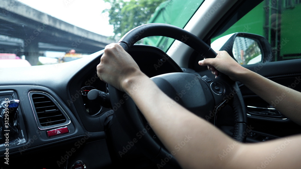 Close-up images of woman hands driving and controling car with confidence and safety which car moving to the Bangkok city Thailand for roadtrip and on the road no traffic jam.