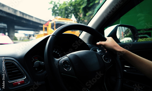 Close-up images of woman hands driving and controling car with confidence and safety which car moving to the Bangkok city Thailand for roadtrip and on the road no traffic jam. © gnepphoto