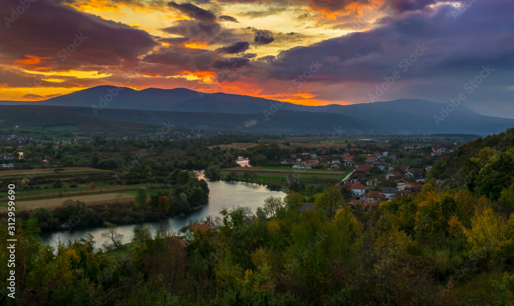 Dramatic sunrise after storm over hillside and river during autumn