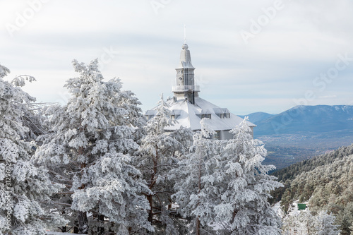 Building tower peeking above the snow-covered trees at the Navacerrada ski resort in Madrid, covered by snow