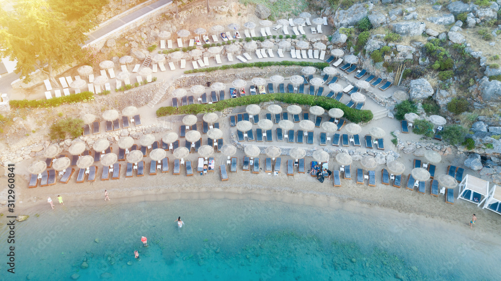 Aerial view of people on the sea beach with sunbeds and umbrellas. Hot sunny summer day.