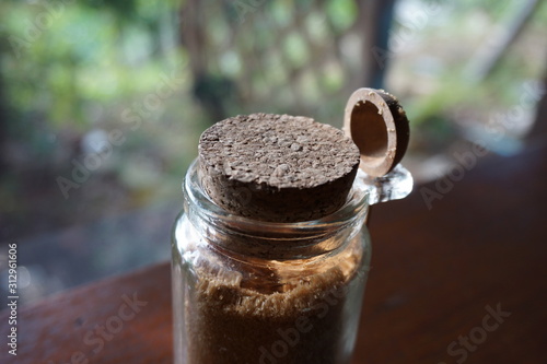 Brown sugar in a transparent bottle with wooden spoon and cork lid.