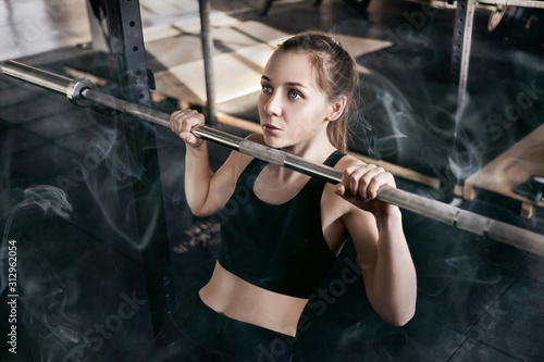 Fitness girl doing exercise n the gym. Dramatic photo with smoke.