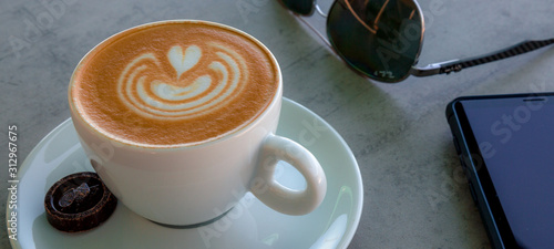 Apetitoso café servido en una taza blanca, con y una bella imagen dibujada en la superficie