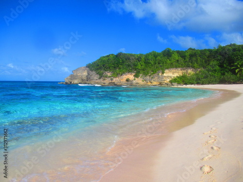 Une plage de sable blanc à côté de la mer turquoise sous le ciel bleu