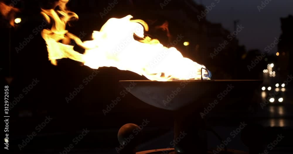 cinematic slow motion shot of fire pot torch burning with car lights in the background at night time