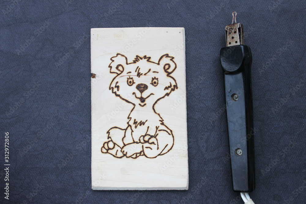 Obraz premium The process of pyrography. Picture with a bear on a board