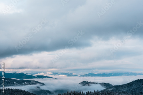scenic view of snowy mountains with white fluffy clouds