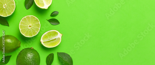 Fresh juicy lime and green leaves on bright green background. Top view flat lay copy space. Creative food background, tropical fruit, vitamin C, citrus. Composition with whole and slices of lime © olgaarkhipenko